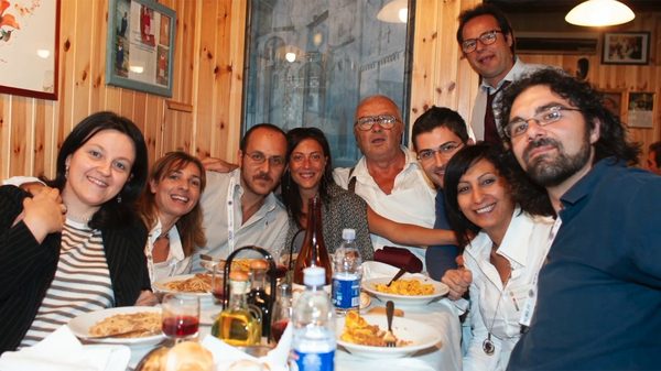 Una tavolata di ospiti felici con Ermes nella saletta di legno