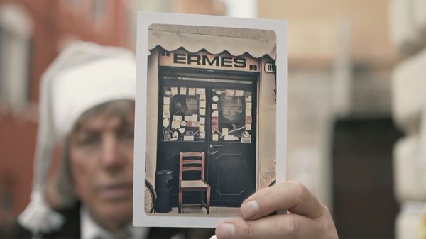 Una vecchia fotografia della vetrina della Trattoria Ermes, tenuta in mano